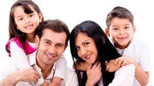 Smiling family of four posing together against a white background.